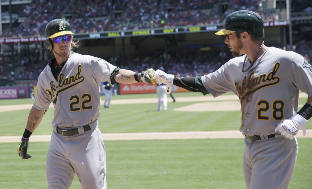 Oakland Athletics Josh Reddick (22) bumps fists with teammate teammate Eric Sogard (28) after Sogard scored on a sacrifice fly by Reddick in the seventh inning of a game against the Texas Rangers in Arlington, Texas, Thursday, June 25, 2015. The Athletics won 6-3. (AP Photo/LM Otero)