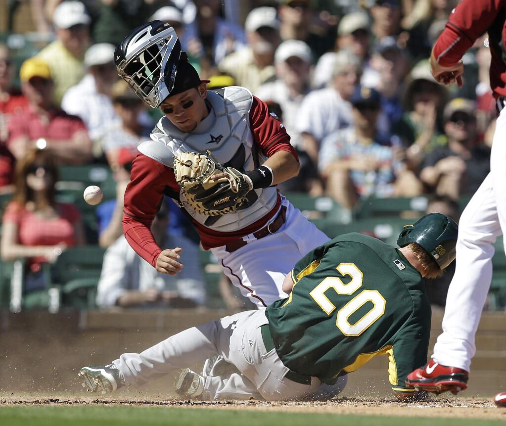 Oakland Athletics' Mark Canha slides in safe at home as Arizona Diamondbacks catcher Oscar Hernandez (23) can't handle the throw during the second inning of a spring training game Friday, March 6, 2015, in Scottsdale, Ariz. Canha scored on a double by Josh Phegley. (AP Photo/Darron Cummings)