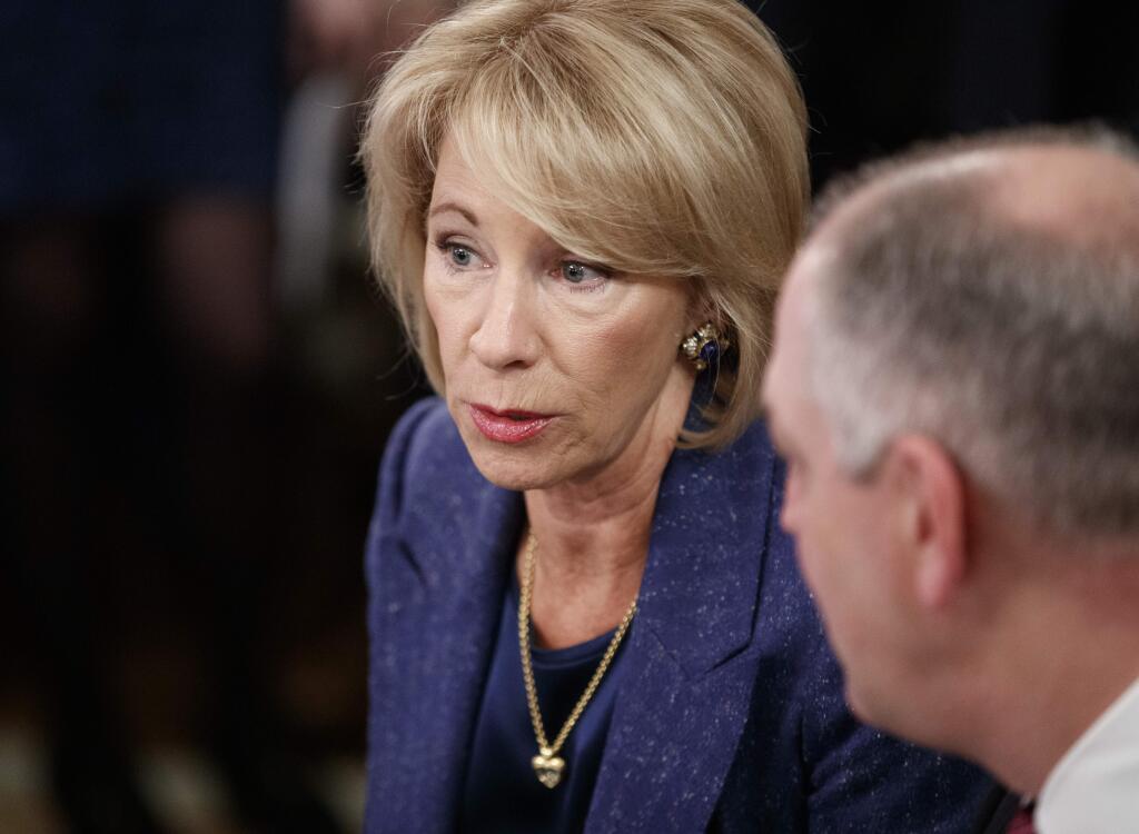 FILE - In this Feb. 25, 2019, file photo, Education Secretary Betsy DeVos, talks with Louisiana Gov. John Bel Edwards before President Donald Trump arrives to speak at the 2019 White House Business Session with Our Nation's Governors in the State Dining Room of the White House in Washington. (AP Photo/Carolyn Kaster, File)