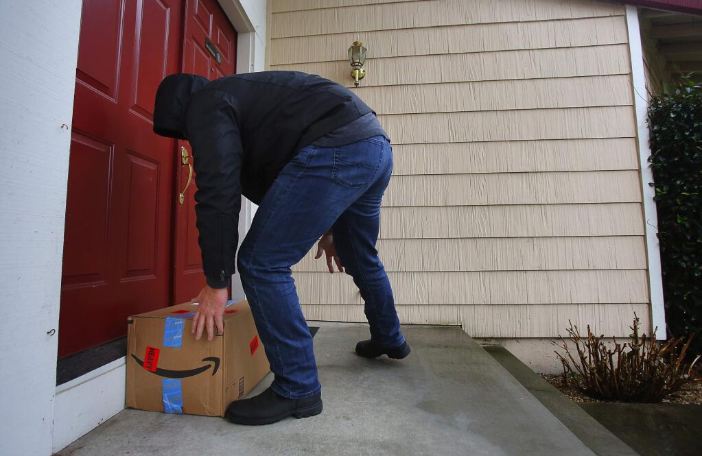 An undercover Sonoma County Sheriff's detective with the property crimes investigation unit leaves a decoy package equipped with a GPS tracking device at the front door of a home in Windsor, on Thursday, December 8, 2016. (Christopher Chung/ The Press Democrat)
