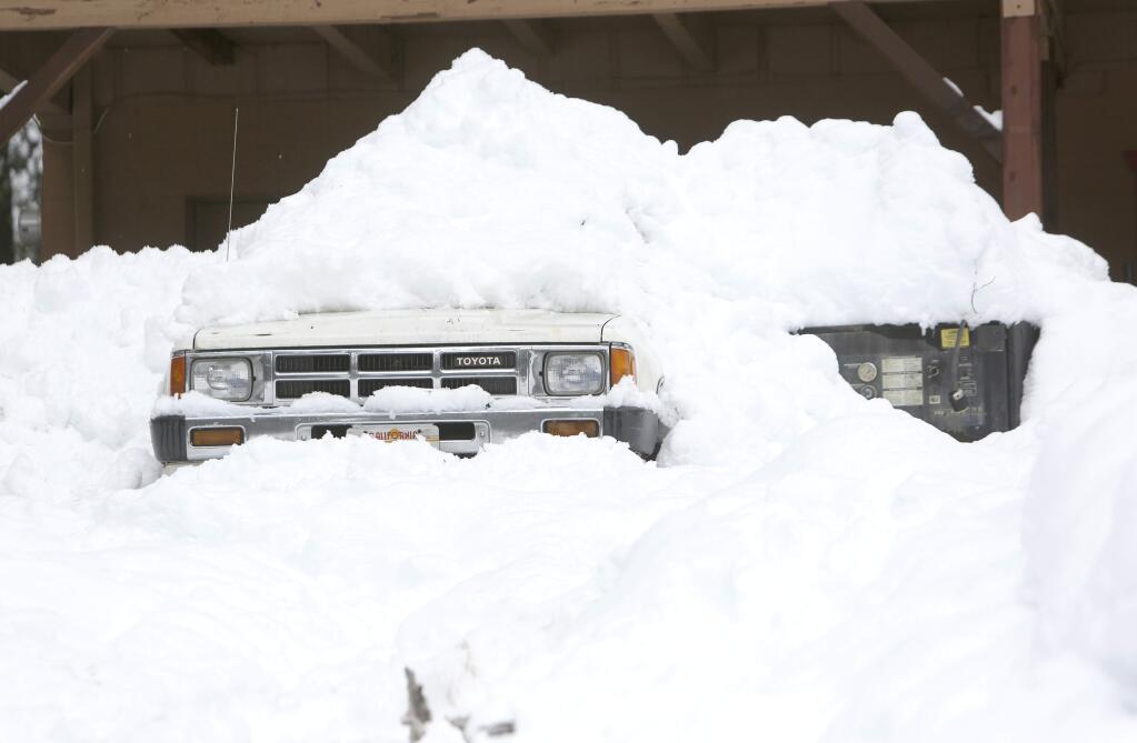 An 80s Toyota pickup is almost all but completely covered in snow in front of this home in Nevada City, Calif., Tuesday, March 17, 2020. (Elias Funez/The Union via AP)