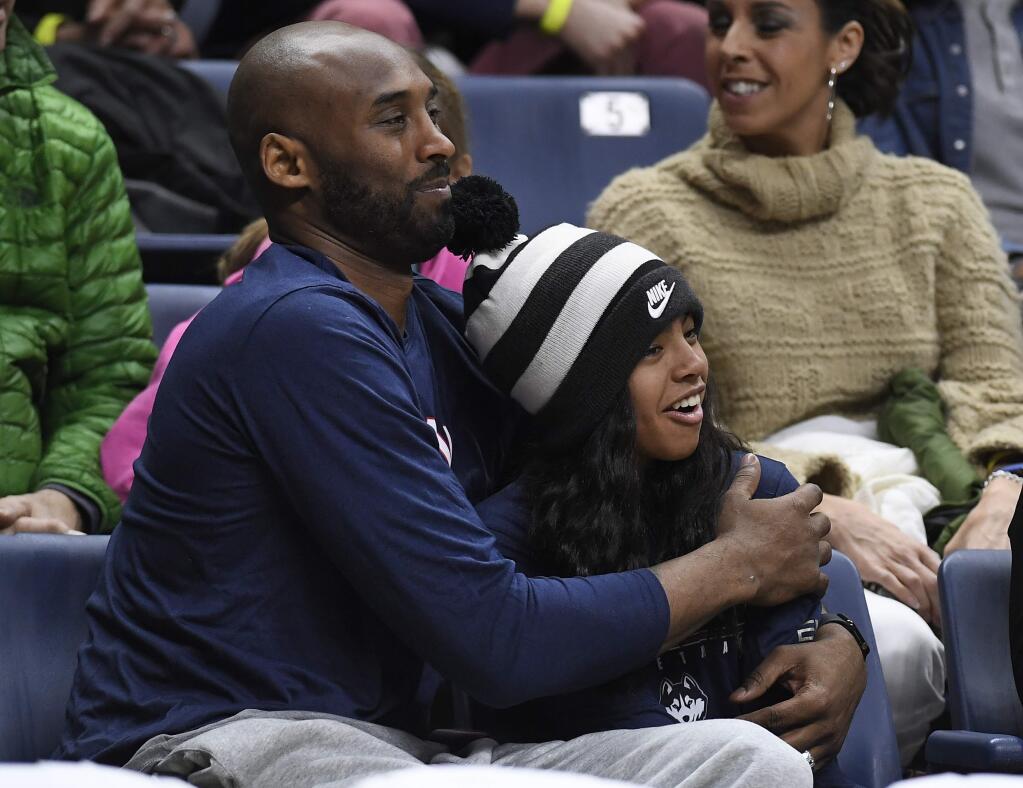 In this March 2, 2019, file photo Kobe Bryant and his daughter Gianna watch the first half of a game between UConn and Houston in Storrs, Conn. (AP Photo/Jessica Hill, File)