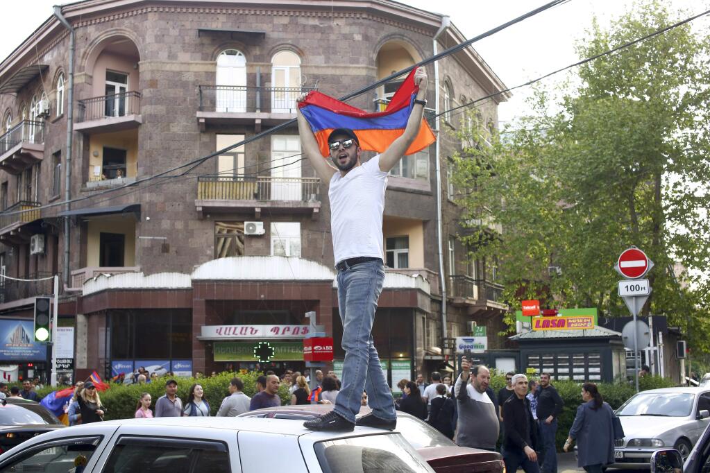 A man waves an Armenian national flag celebrating Armenian Prime Minister's Serzh Sargsyan's resignation in Republic Square in Yerevan, Armenia, Monday, April 23, 2018. Armenian Prime Minister Serzh Sargsyan resigned unexpectedly on Monday to quell massive anti-government protests over what critics feared was his effort to seize power for life. (Hrant Khactaryan/PAN Photo via AP)