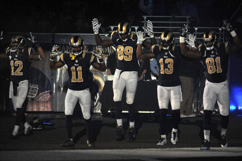 Members of the St. Louis Rams raise their arms in awareness of the events in Ferguson, Mo., as they walk onto the field during introductions before an NFL football game against the Oakland Raiders, Sunday, Nov. 30, 2014, in St. Louis. The players said after the game, they raised their arms in a 'hands up' gesture to acknowledge the events in Ferguson. (AP Photo/L.G. Patterson)