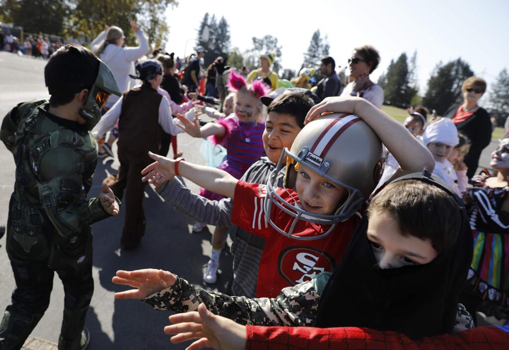 Riebli Elementary School first graders Bryan Daher, 6, right, and Brodie Pearson, 6, reach their hands out for high fives their during the Halloween parade at Mark West Elementary School in Santa Rosa, on Tuesday, October 31, 2017. (BETH SCHLANKER/ The Press Democrat)