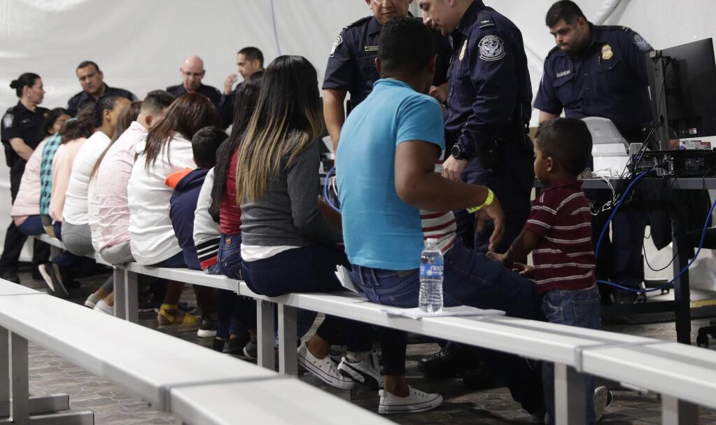 FILE - In this Sept. 17, 2019, file photo, migrants who are applying for asylum in the United States go through a processing area at a new tent courtroom at the Migration Protection Protocols Immigration Hearing Facility, in Laredo, Texas. (AP Photo/Eric Gay, File)