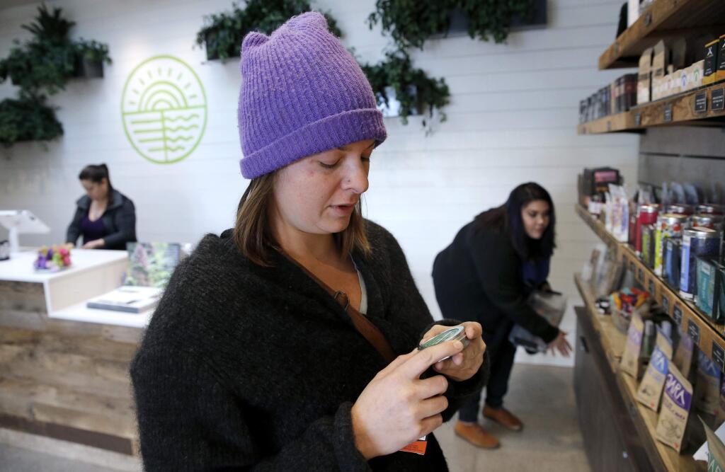 Hanna Chort does some holiday shopping as employees Adriana Snider, right, and Jennifer Alcocer, left, work at Solful cannabis dispensary in Sebastopol, on Tuesday, Dec. 19, 2017. (BETH SCHLANKER/ The Press Democrat)