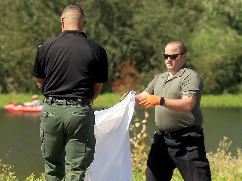 Officials of a recovery service contracted by the Sonoma County Sheriff's Department prepare to cover the body of an adult male that was found in the Russian River east of Healdsburg Memorial Beach, Monday Sept. 5, 2016 in Healdsburg. (Kent Porter / The Press Democrat) 2016