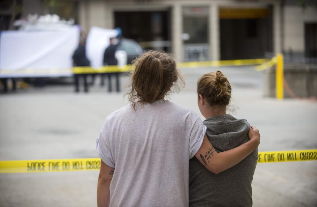Two women embrace while watching sheriff's deputies move the body of a person who died when a fourth floor balcony collapsed in Berkeley, Calif. on Tuesday, June 16, 2015. The two said they knew the victims of the collapse. Berkeley police say several people are dead and others injured after a balcony fell shortly before 1 a.m., near the University of California, Berkeley. (AP Photo/Noah Berger)