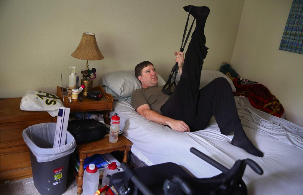 -Joel Billman stretches at home as part of his rehabilitation. He is learning to walk again after being paralyzed from a fall while hiking on Fitch Mountain in October 2013.