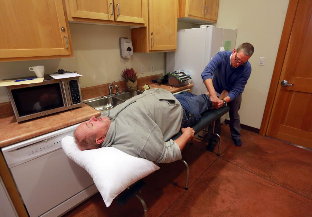 Acupuncturist Graham Lankford used a needle on the calf of Joe Trinidade at the the Community Holistic Clinic a the Colgan Meadows Community Room in Santa Rosa on Friday. (JOHN BURGESS / The Press Democrat)