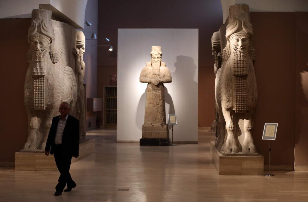 FILE - In this March 1, 2015. file photo, a man at Iraq's National Museum in Baghdad walks past two ancient Assyrian human-headed winged bull statues. (AP Photo/Karim Kadim, File)