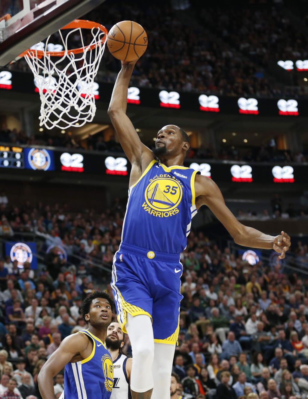 Golden State Warriors forward Kevin Durant dunks as teammate Damian Jones and Utah Jazz guard Ricky Rubio, rear, watch in the first half Friday, Oct. 19, 2018, in Salt Lake City. (AP Photo/Rick Bowmer)