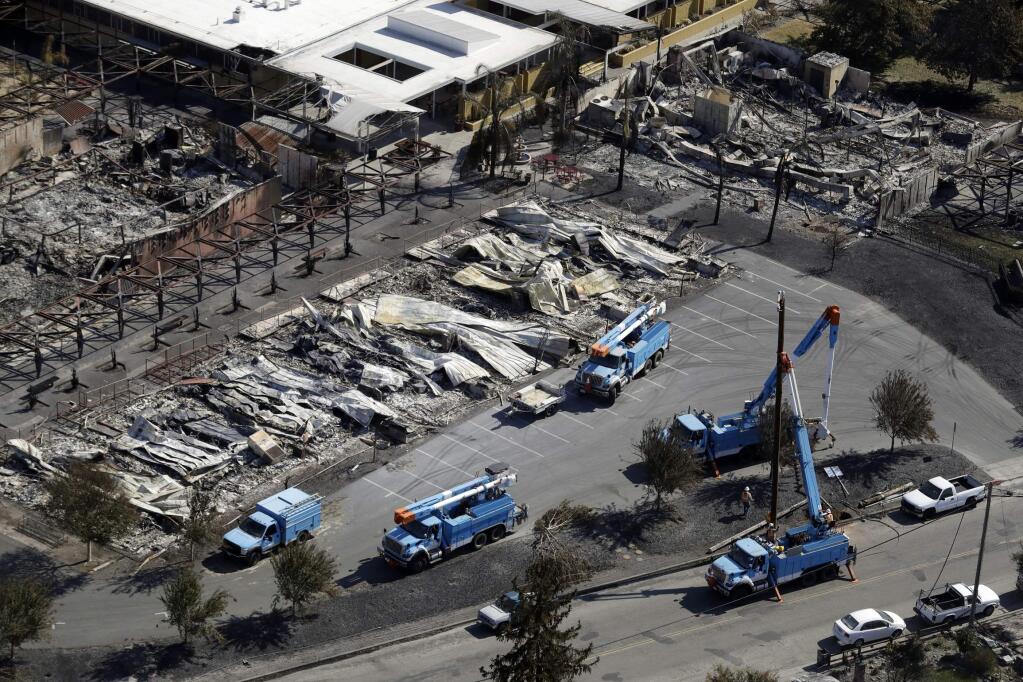 FILE - In this Oct. 14, 2017, file photo, PG&E crews work on restoring power lines in a fire ravaged neighborhood in an aerial view in the aftermath of a wildfire in Santa Rosa, Calif. (AP Photo/Marcio Jose Sanchez, File)