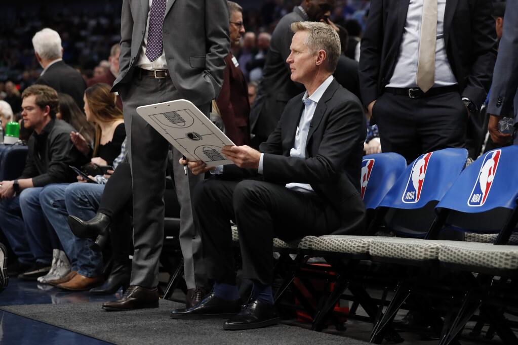 Golden State Warriors head coach Steve Kerr sits on the bench before the start of an NBA basketball game against the Dallas Mavericks in Dallas, Wednesday, Nov. 20, 2019. (AP Photo/Tony Gutierrez)