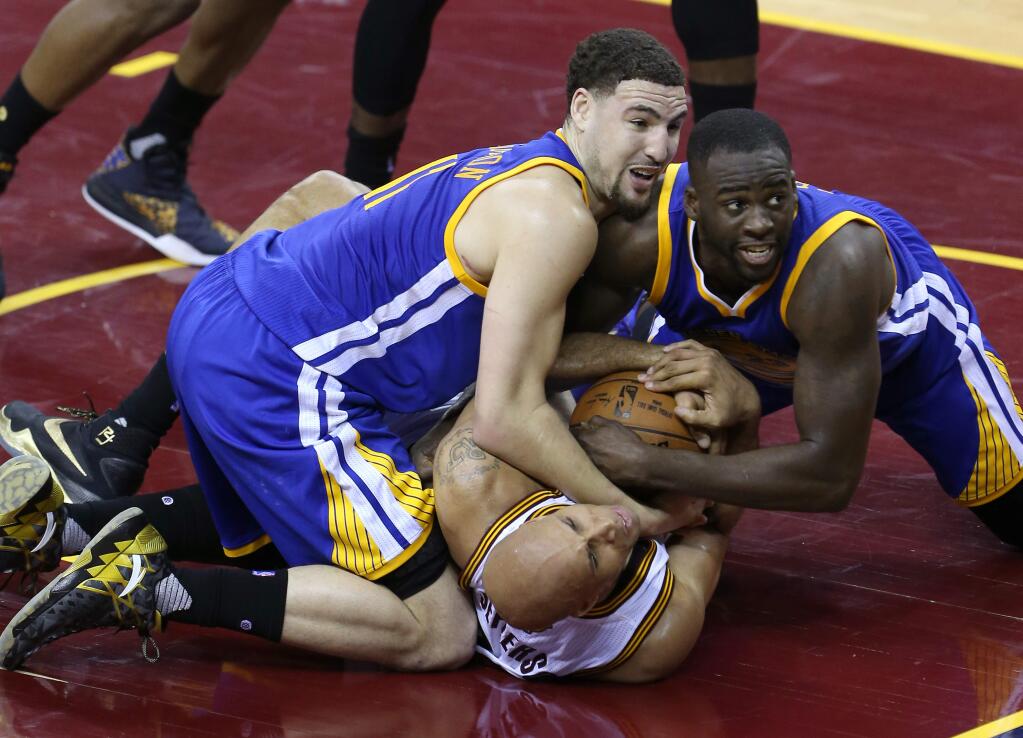 Golden State Warriors' Klay Thompson and Draymond Green wrestle with Cleveland Cavaliers' Richard Jefferson for the ball during their game in Cleveland on Friday, June 10, 2016. The Warriors defeated the Cavaliers 108-97. (Christopher Chung / The Press Democrat)