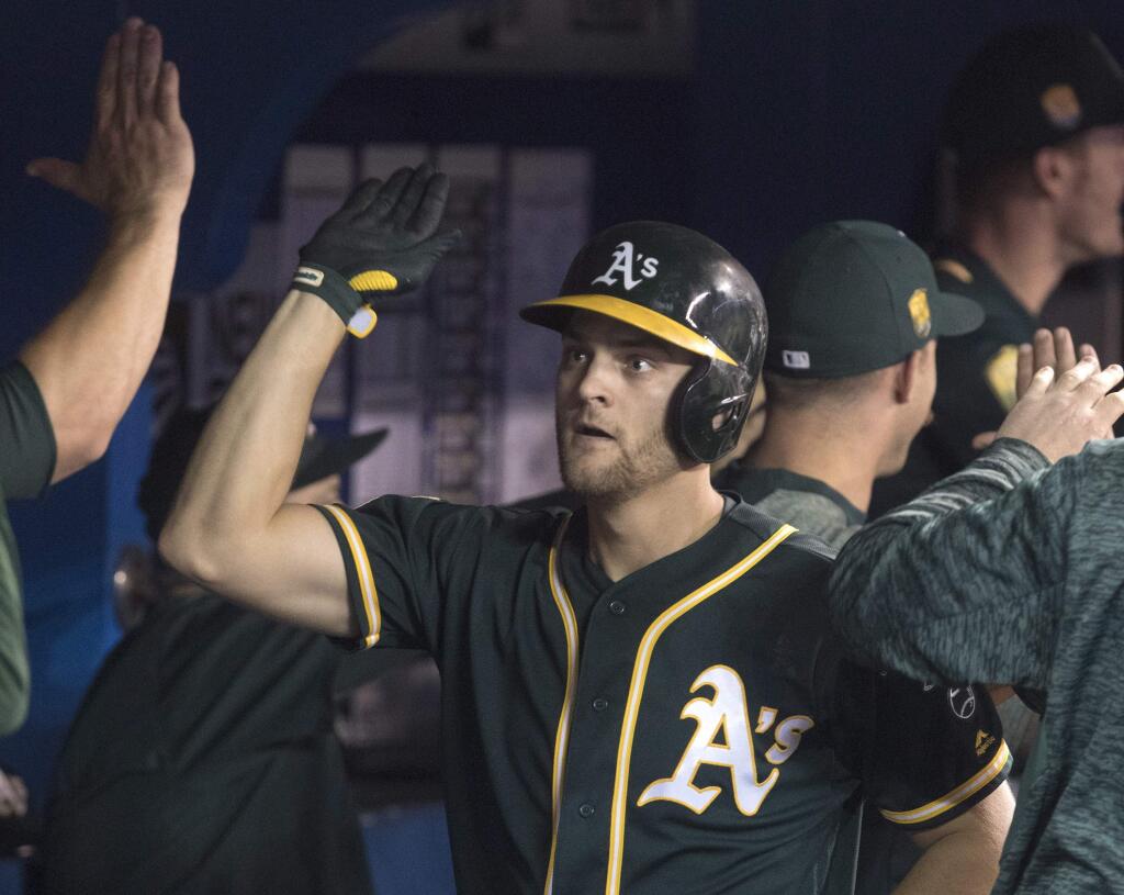 Oakland Athletics' Chad Pinder celebrates in the dugout after hitting a grand slam against the Toronto Blue Jays in the eighth inning of a baseball game against the Oakland Athletics in Toronto, Saturday, May 19, 2018. (Fred Thornhill/The Canadian Press via AP)