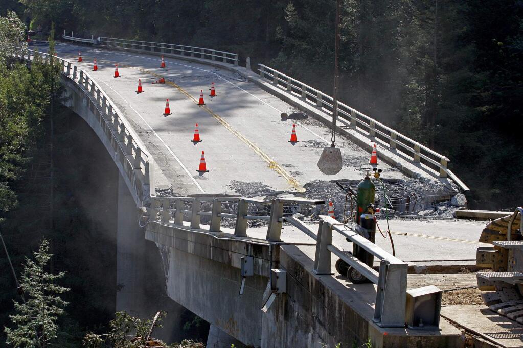 FILE- In this March 16, 2017, file photo, crews use a wrecking ball attached to a crane on the demolition of the storm-damaged Pfeiffer Canyon Bridge in Big Sur, Calif. The crumbling bridge along the California coast has stranded residents in the popular Big Sur area and closed part of iconic Highway 1. (Vern Fisher/Monterey Herald via AP, File)