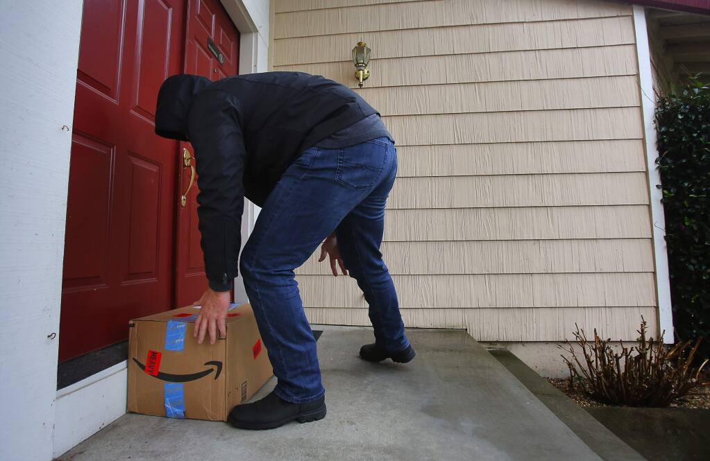 An undercover Sonoma County sheriff's detective with the property crimes investigation unit leaves a decoy package equipped with a GPS tracking device at the front door of a home in Windsor, on Thursday, Dec. 8, 2016. (Christopher Chung/ The Press Democrat, 2016)