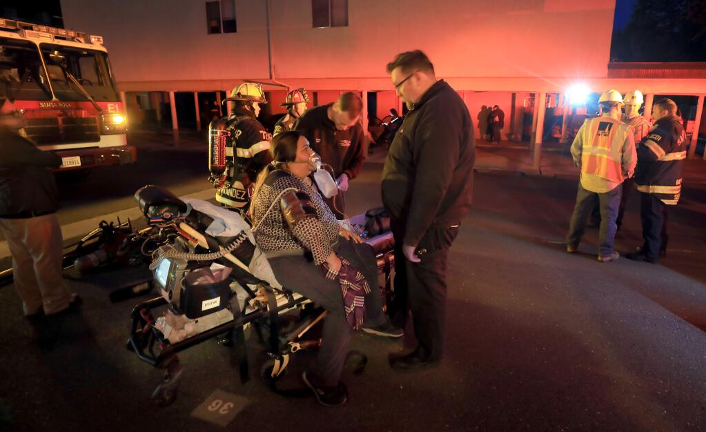 Paramedics tend to a resident who had a little smoke inhalation at the Nueva Vista Apartments at McBride and Steele Lane in Santa Rosa, Thursday, April 4, 2019, after fire ripped through part of the complex. (Kent Porter / The Press Democrat) 2019