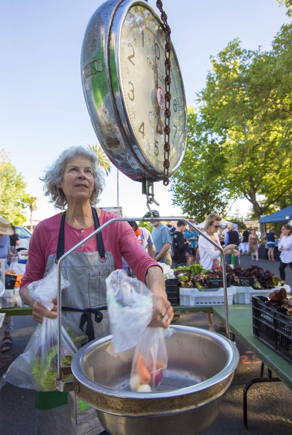 Robbi Pengelly/Index-Tribune file photo 2017Candi Edmondson, of Paul's Produce, weighs a customer's purchase at the first Farmers Market in 2017. The market opens tonight and runs every Tuesday night through the end of September on the Plaza. The market is open from 5:30 p.m. until dusk.