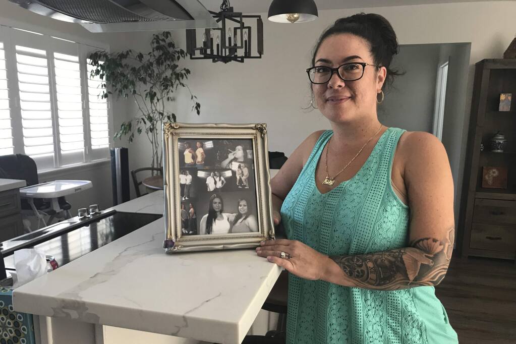In this photo taken Sept. 26, 2019, is Amika Mota holding a framed collage of her 'prison family,' at her home in the San Francisco Bay area. Previously hidden documents reveal details of sexual abuse inside California's women's prisons. Mota is trying to change that. She spent most of a nine-year prison sentence for vehicular manslaughter at the Central California Women's Facility in Chowchilla, north of Fresno in the Central Valley. She said she and other incarcerated women put up with sexual advances because they depended on correctional officers for access to clean laundry, phone calls, tampons, time out of their cells and other basic needs. (Julie Small/KQED via AP)