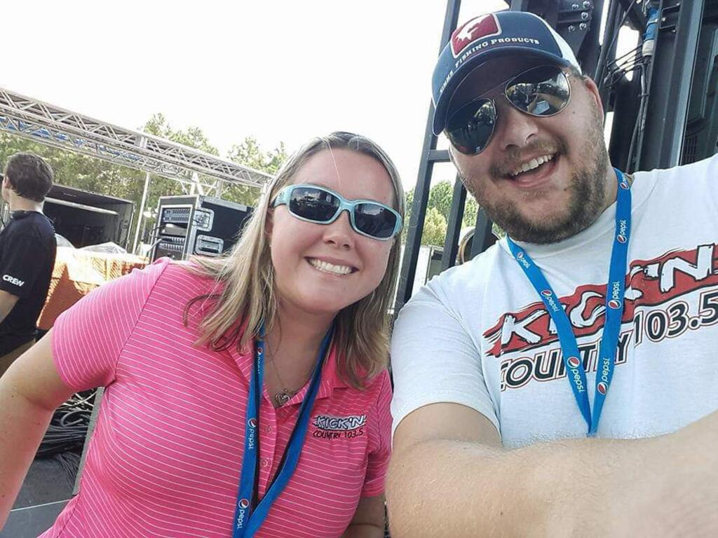 In this Sept, 2, 2017 photo provided by Sean Streeter, he takes a selfie with Tiffany Dunning, left, at the Pepsi Gulf Coast Jam in Panama City Beach, Fla. Even though their radio station has shut down, the radio hosts are keeping Florida Panhandle residents informed on their Facebook page about where to find food, ice and medicine in the wake of Hurricane Michael's destruction. (AP Photo/ Hand Out by Sean Streeter)