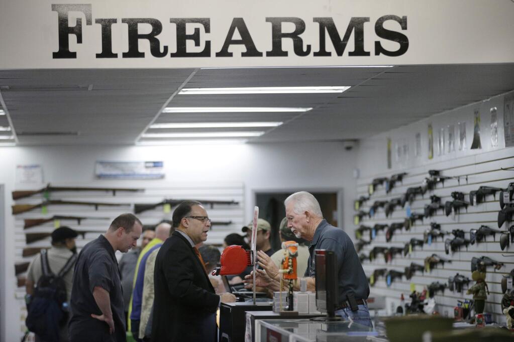 FILE - In this Dec. 9, 2015, file photo, sales associate Mike Conway, right, shows Paul Angulo a pistol at Bullseye Sport gun shop in Riverside, Calif. A U.S. judge has struck down a nearly century-old California law that banned gun shops from advertising handguns on their premises. Judge Troy Nunley in Sacramento ruled Tuesday, Sept. 11, 2018, that the law restricted speech in violation of the First Amendment. The ruling came in a lawsuit filed in 2014 by several gun dealers who were fined by the state for handgun ads. The 1923 law banned any handgun ads at gun shops that were visible from outside the store. Judge Nunley noted that gun shops could put up a 15-foot display of a sporting rifle or place ads for handguns elsewhere such as on a billboard blocks away. (AP Photo/Jae C. Hong, File)