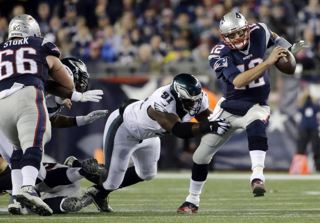 In this Dec. 6, 2015, file photo, New England Patriots quarterback Tom Brady (12) scrambles away from Philadelphia Eagles defensive end Fletcher Cox (91) during the first half of an NFL football in Foxborough, Mass. (AP Photo/Steven Senne, File)