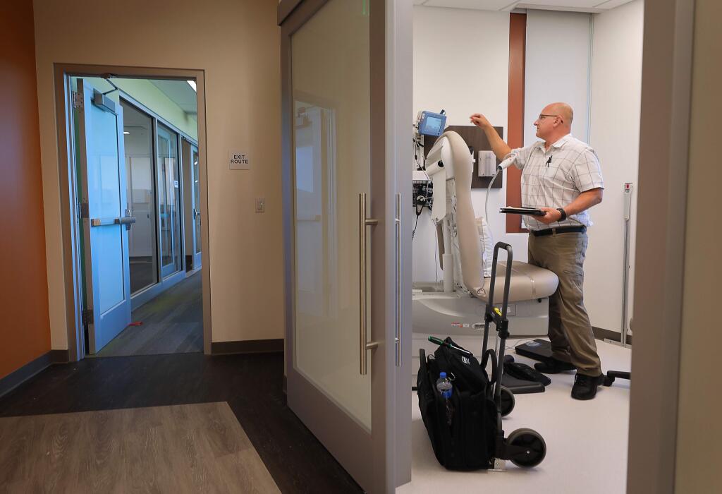 Mike Crenshaw performs electrical safety checks on medical equipment in an examination room at the Santa Rosa Community Health Vista Campus, in Santa Rosa on Tuesday, August 13, 2019. The campus has been closed since it sustained damage in the Tubbs fire(Christopher Chung/ The Press Democrat)