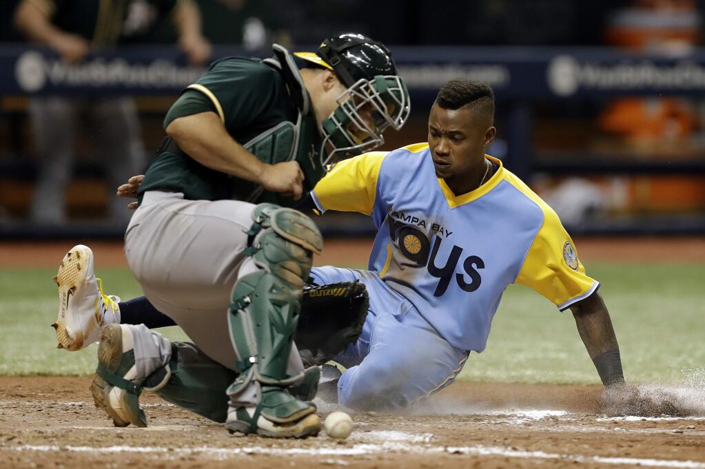 Tampa Bay Rays' Tim Beckham, right, scores on an error by Oakland Athletics catcher Josh Phegley during the sixth inning of the first game of a scheduled baseball doubleheader Saturday, June 10, 2017, in St. Petersburg, Fla. (AP Photo/Chris O'Meara)