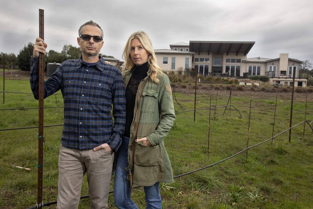 Jad and Stacie Elkhoury stand in front of their Sonoma home, which was spared from destruction in the Nuns fire, but suffered some smoke damage. The couple's insurance company recently dropped coverage for their vacation home in Truckee because it's in a heavy brush zone. (photo by John Burgess/The Press Democrat)