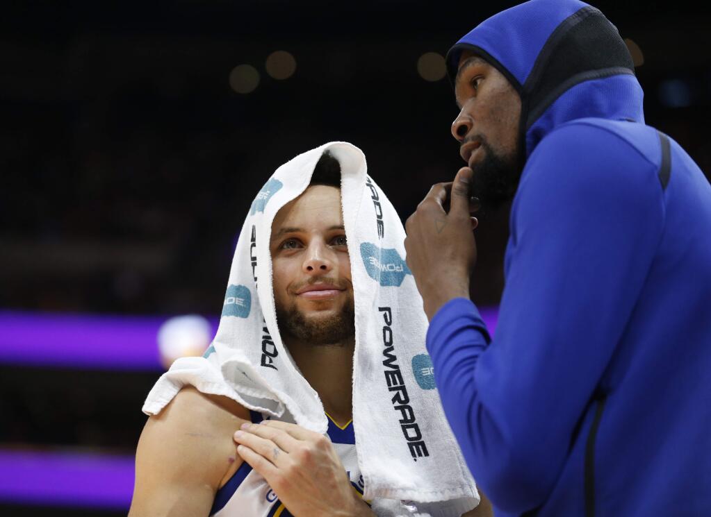 The Golden State Warriors' Stephen Curry, left, and Kevin Durant, right, speak during a timeout in the second half against the Utah Jazz Tuesday, Jan. 30, 2018, in Salt Lake City. (AP Photo/Rick Bowmer)