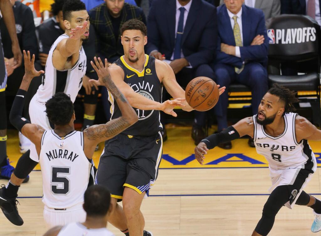 Golden State Warriors guard Klay Thompson passes the ball as the San Antonio Spurs defense collapses on him, during their game in Oakland on Monday, April 16, 2018. (Christopher Chung/ The Press Democrat)