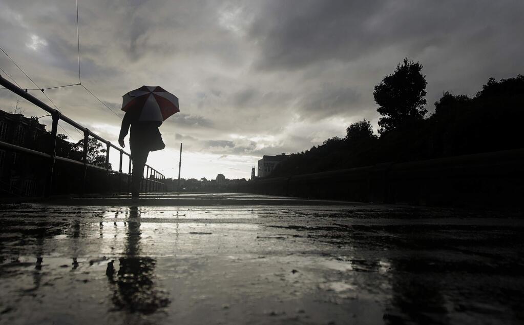 File - In this March 5, 2019, file photo, a man walks with an umbrella in the rain in San Francisco. A cold front traveling down to Northern California from the Gulf of Alaska is expected to dump at least a foot of snow in higher elevations of the Sierra Nevada weeks before the start of summer. National Weather Service meteorologist Brendon Rubin-Oster says the first storm will arrive Wednesday, May 15, 2019, and will continue through Thursday. (AP Photo/Jeff Chiu, File)