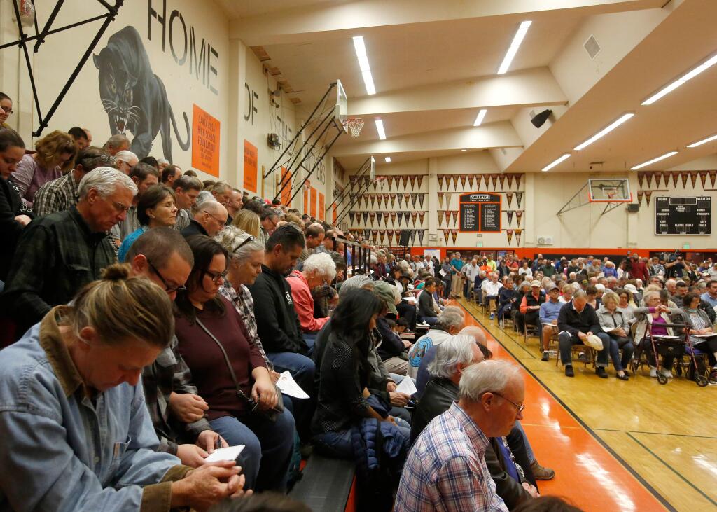 Santa Rosa residents bow their heads in a moment of silence for people who lost their lives in the Tubbs Fire, during a community meeting at Santa Rosa High School in Santa Rosa, California on Thursday, October 19, 2017. (Alvin Jornada / The Press Democrat)