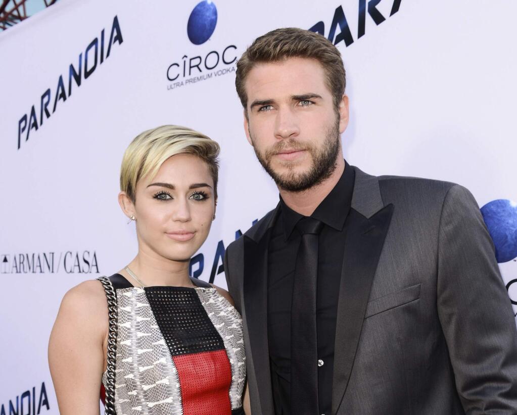 FILE - In this Aug. 8, 2013, file photo, actor Liam Hemsworth and singer and actress Miley Cyrus arrive on the red carpet at the US premiere of the feature film 'Paranoia' at the DGA Theatre in Los Angeles. Cyrus and Hemsworth have tied the knot amid reports the couple got married in a secret wedding ceremony. Cyrus posted three black-and-white photos of her and Hemsworth on the singer's Instagram and Twitter accounts on Wednesday, Dec. 26, 2018. (Photo by Dan Steinberg/Invision/AP, File)