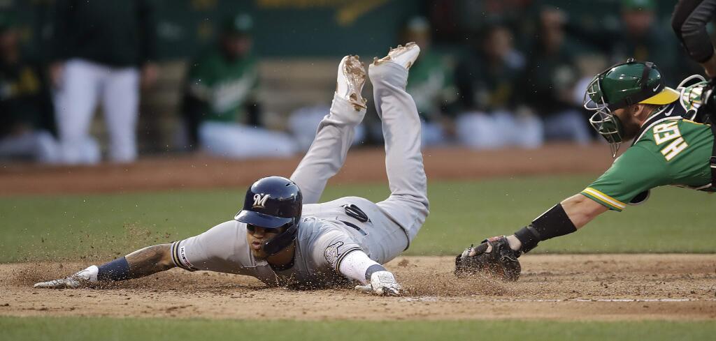 The Milwaukee Brewers' Orlando Arcia, left, slides to score past the tag of Oakland Athletics catcher Chris Herrmann during the third inning Wednesday, July 31, 2019, in Oakland. (AP Photo/Ben Margot)