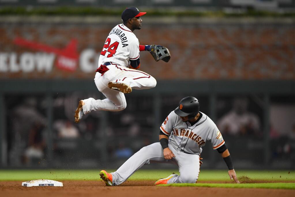 Atlanta Braves second baseman Adeiny Hechavarria throws above the San Francisco Giants' Cristhian Adames after forcing him out at second base for a double play on Mauricio Dubon at first base during the fifth inning, Saturday, Sept. 21, 2019, in Atlanta. (AP Photo/John Amis)
