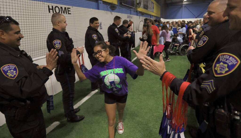 Victoria Avala, a student of Comstock Middle School, is congratulated by Santa Rosa Fire and Police, Monday Dec. 11, 2017 after participating in Special Olympic soccer matches at the Epicenter in Santa Rosa. (Kent Porter / Press Democrat) 2017
