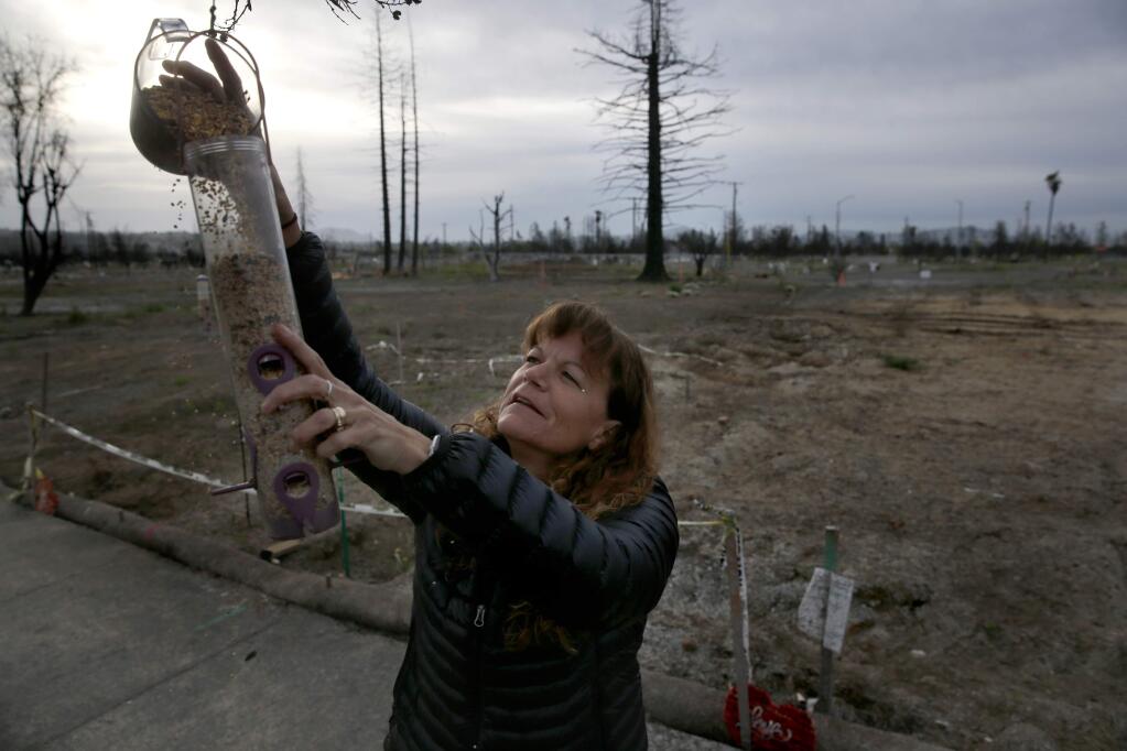 Teri O'Donnell fills a bird feeder at the site of her former home on Hopper Ave. on Wednesday, April 18, 2018 in Santa Rosa, California . (BETH SCHLANKER/The Press Democrat)
