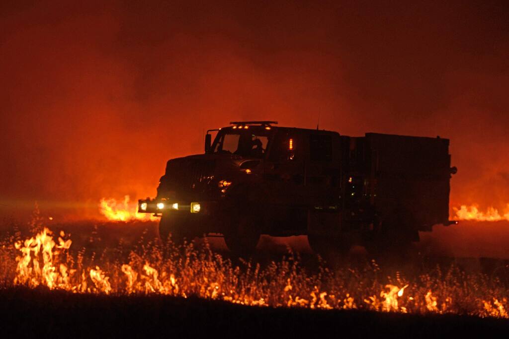 A California Office of Emergency Services fire engine drives on a dirt road flanked by grass fires during the fifth day of the Rocky Fire near Clearlake Oaks, California on Sunday, August 2, 2015. (Alvin Jornada for The Press Democrat)