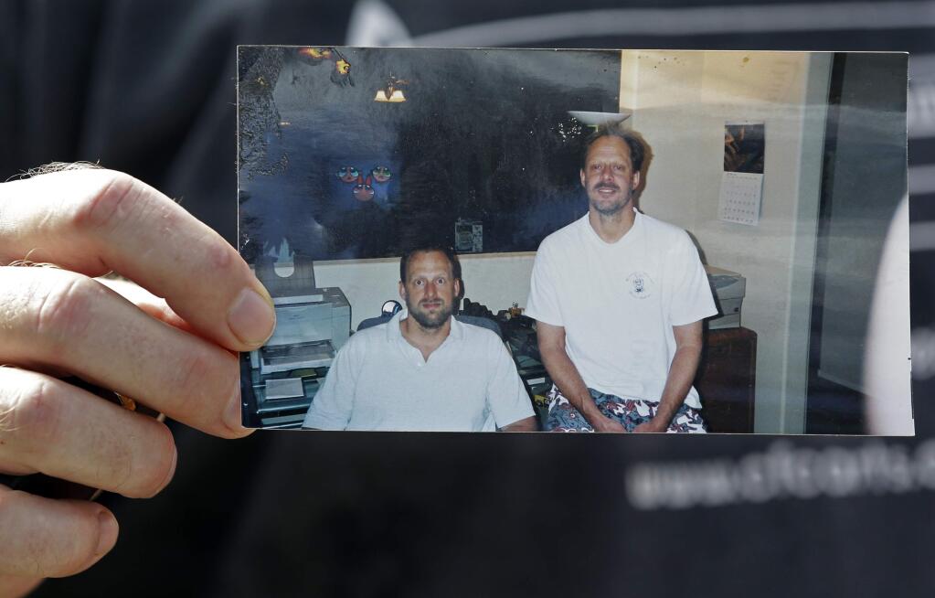 FILE - In this Oct. 2, 2017 file photo, Eric Paddock holds a photo of himself, at left, and his brother, Las Vegas shooter Stephen Paddock, at right, outside his home in Orlando, Fla. Officials in Las Vegas say the cremated remains of the gunman in the worst mass shooting in modern U.S. history have been turned over to his brother. Clark County Coroner John Fudenberg said in a statement that Stephen Paddock's ashes were given to Paddock's brother, Eric Paddock, Thursday, Jan. 18, 2017. (AP Photo/John Raoux, File)