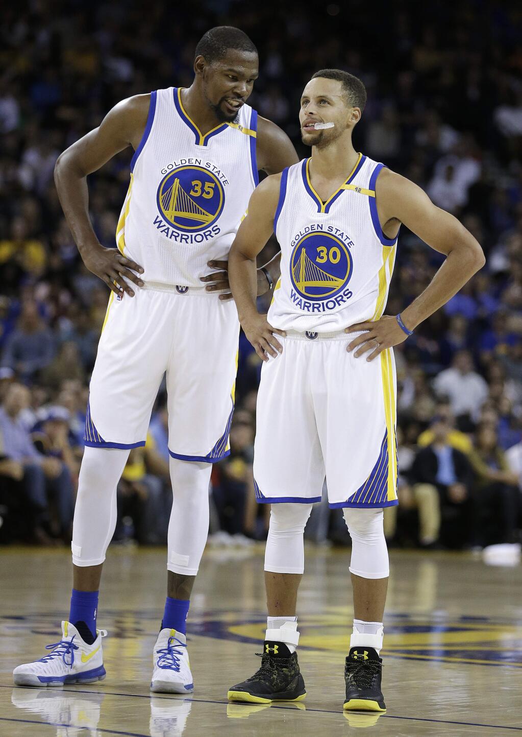 Golden State Warriors' Kevin Durant, left, speaks with Stephen Curry (30) during the first half of a pre-season NBA basketball game against the Los Angeles Clippers on Tuesday, Oct. 4, 2016, in Oakland, Calif. (AP Photo/Ben Margot)