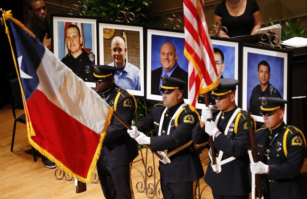 The Dallas Police color guard presents the colors before the photos of five fallen officers being remembered during an interfaith memorial service at the Morton H. Meyerson Symphony Center in Dallas, Tuesday, July 12, 2016. Four Dallas police officers and one Dallas Area Rapid Transit (DART) officer were gunned down last week in downtown Dallas at a protest rally. The victims are depicted, from left, Dallas PD officer Michael Krol, DART officer Brent Thompson, Dallas police Sr. Cpl. Lorne Ahrens, Dallas police Sgt. Michael Smith, and Dallas police Officer Patrick Zamarripa. (Tom Fox/The Dallas Morning News via AP)
