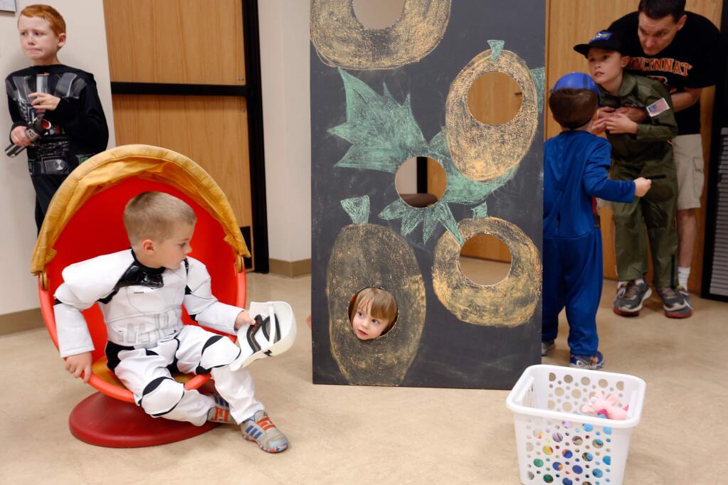 Alexis Garfinkel, 3, center, looks through a game board at stormtrooper Max Hoggan, 4, during a Halloween party where children with special needs can practice trick or treating by Matrix Parent Network and Resource Center in Santa Rosa, California on Sunday, October 25, 2015. (Alvin Jornada / The Press Democrat)