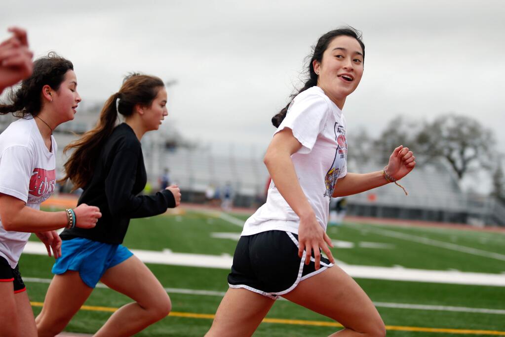 Santa Rosa High School's Aimee Holland, right, looks back and grins at a teammate as they begin a 600-meter run during track practice, in Santa Rosa, California on Wednesday, January 6, 2016. (Alvin Jornada / The Press Democrat)