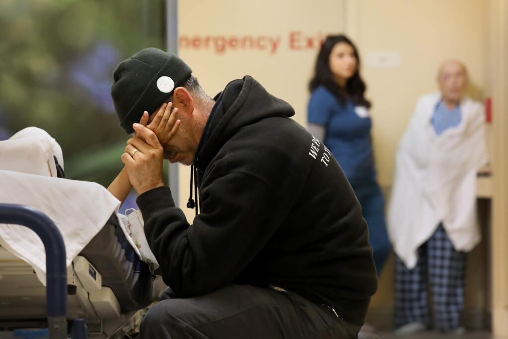 With no rooms available, Juan Sedano holds the hand of his son Daniel, 7, who lies in a hospital bed in the hallway of the Emergency Department at Santa Rosa Memorial Hospital in Santa Rosa on Tuesday, Dec. 3, 2019. (BETH SCHLANKER/ PD)