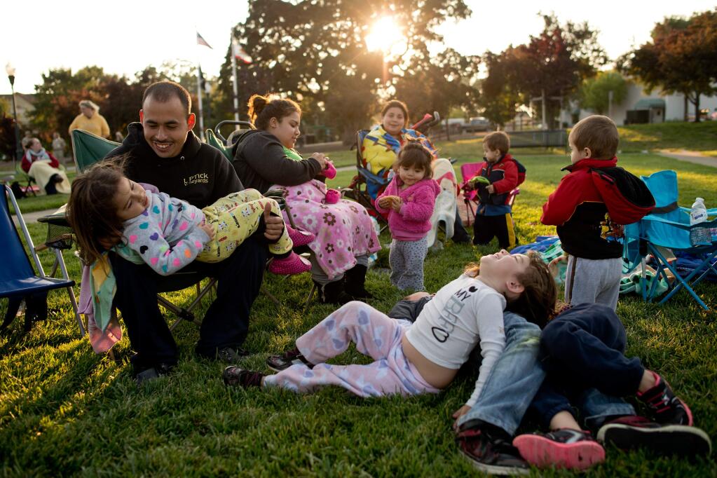 8/3/2013: T4:PC: Jesus Jimenez, left, Isabel Gonzalez Jimenez and Esmeralda Bustamante watch their children play together before the start of the Tuesday Night Movie on the Town Green in Windsor, Calif., on July 30, 2013. (Alvin Jornada / For The Press Democrat)
