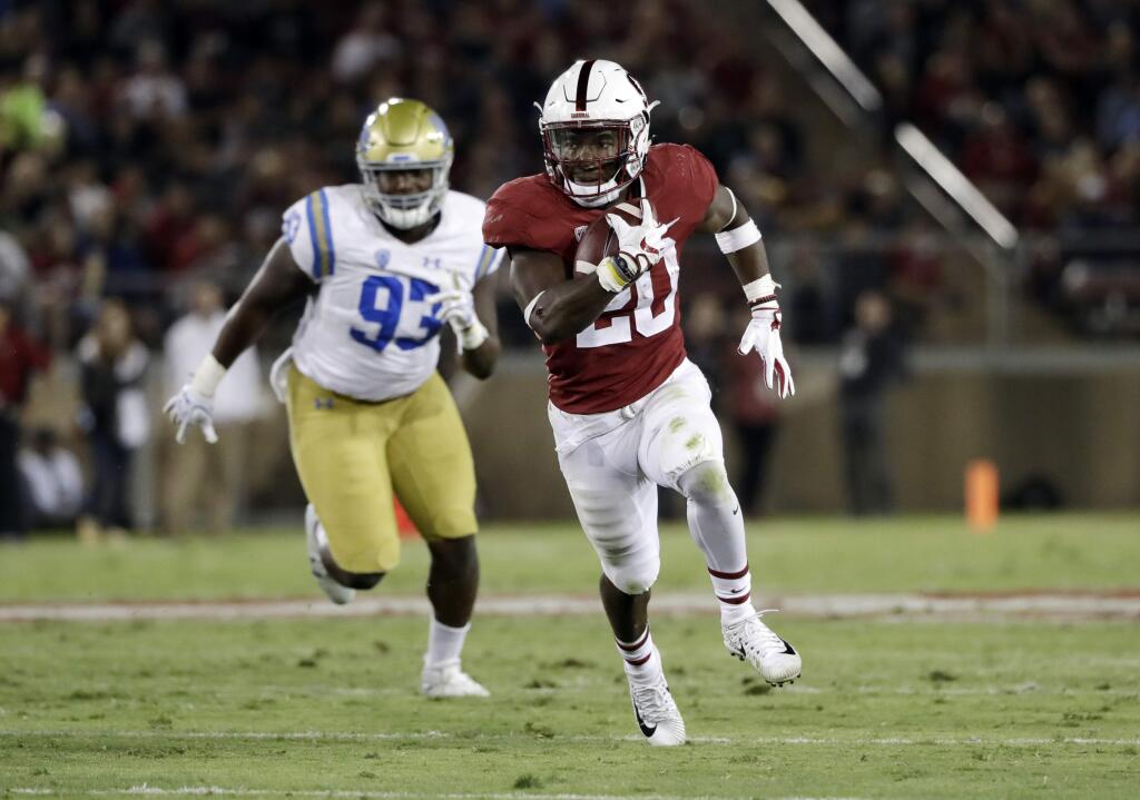 Stanford running back Bryce Love, right, runs past UCLA defensive lineman Chigozie Nnoruka during the first half Saturday, Sept. 23, 2017, in Stanford. (AP Photo/Marcio Jose Sanchez)